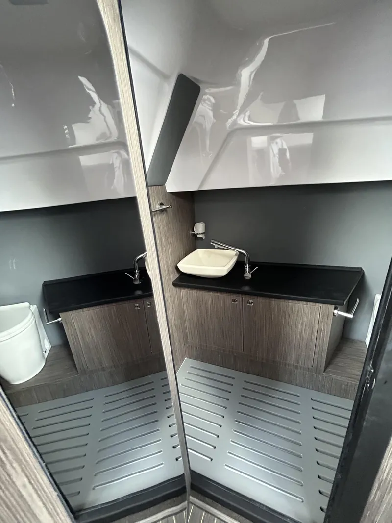 Slide: The Image of 2025 Ranieri 330LX boat interior bathroom with modern sink and wood accents. - 48