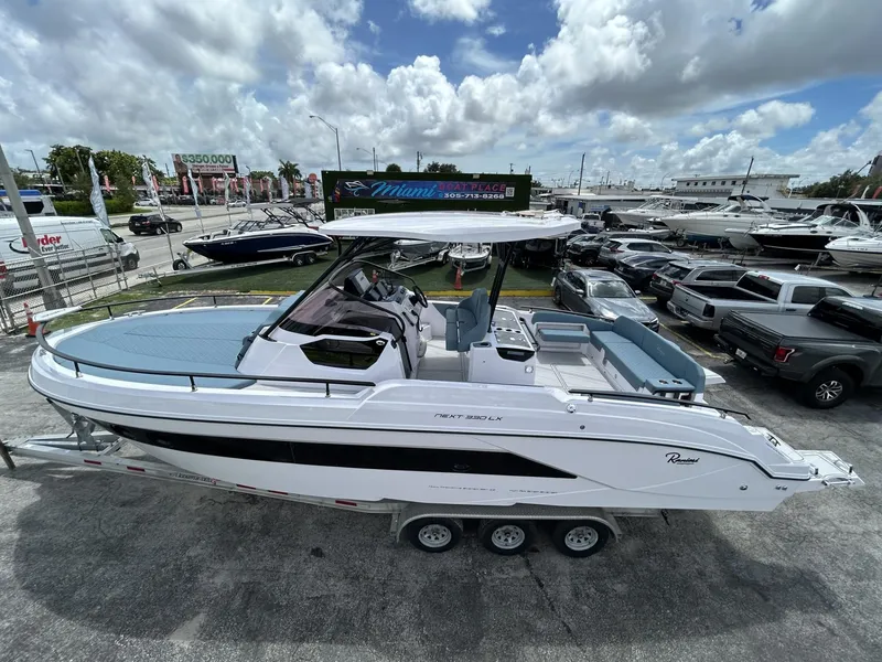 Slide: The Image of 2025 Ranieri 330LX boat on display at a dealership under a cloudy sky. - 9