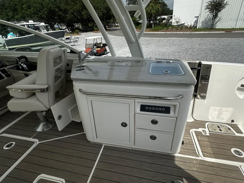 Slide: The Image of 2016 Boston Whaler 320 Vantage boat interior with kitchenette and seating area. - 14