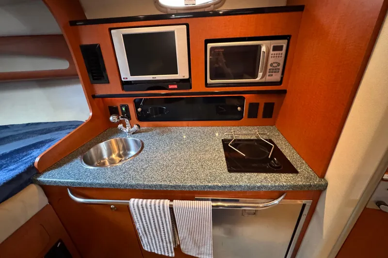 Slide: The Image of 2005 Chaparral Signature 270 interior kitchen with sink, stove, microwave, and TV. - 15