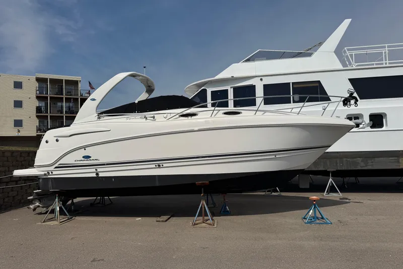 Slide: The Image of 2005 Chaparral Signature 270 boat on stands, parked beside a larger vessel. - 21