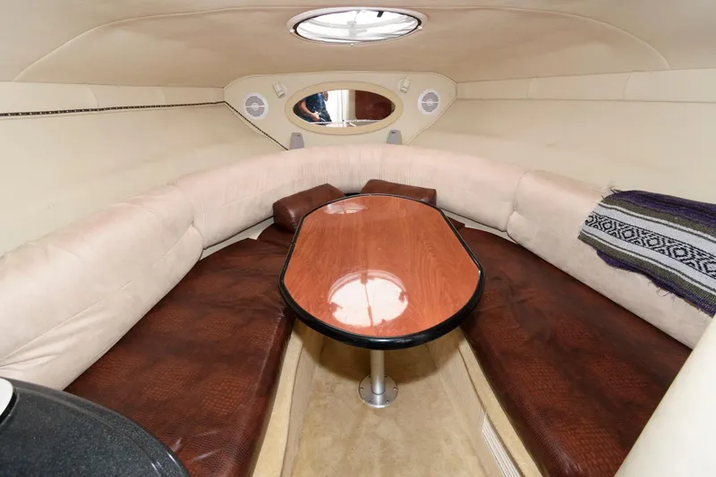 Slide: The Image of Interior of a 2005 Monterey 250 Cruiser boat with cushioned seating and a wooden table. - 9