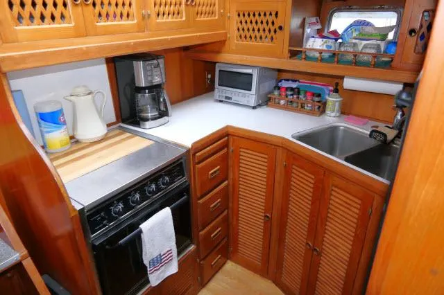 Slide: The Image of Compact kitchen in a 1986 Nova 36 Sundeck boat with wooden cabinets and modern appliances. - 17