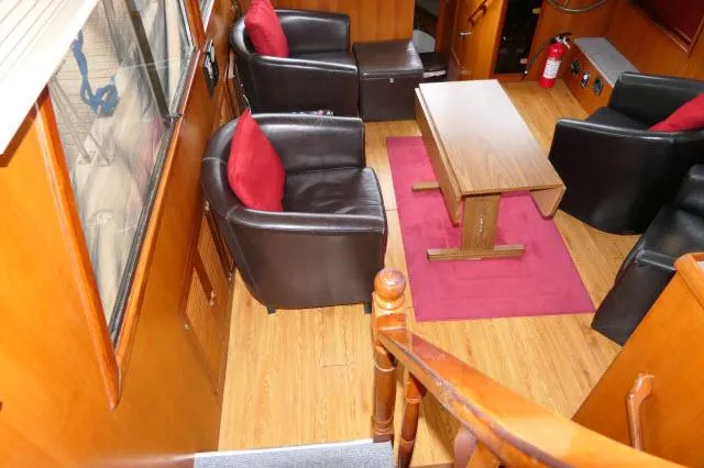 Slide: The Image of Interior of 1986 Nova 36 Sundeck with leather chairs, red cushions, and wooden table. - 2