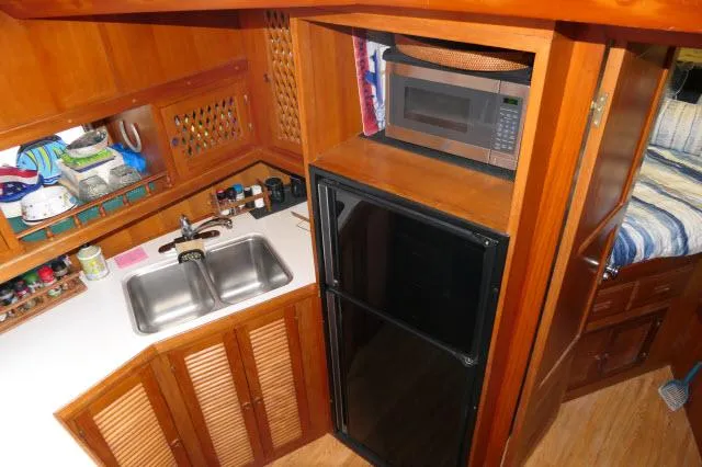 Slide: The Image of 1986 Nova 36 SUNDECK kitchen with sink, fridge, microwave, and wooden cabinetry. - 25