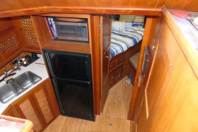 Slide: The Image of 1986 Nova 36 SUNDECK interior with kitchenette, microwave, fridge, and cozy sleeping area. - 26