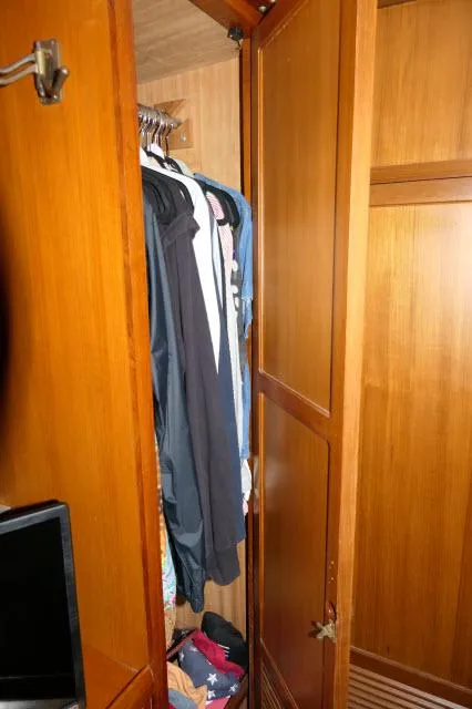 Slide: The Image of Wooden closet with hanging clothes inside a 1986 Nova 36 Sundeck boat. - 37