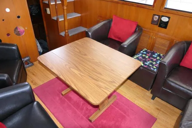 Slide: The Image of Interior of 1986 Nova 36 Sundeck with wooden table, chairs, and red accents. - 7