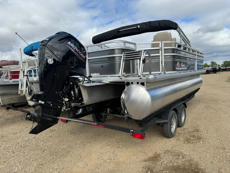 Slide: The Image of 2024 Sun Tracker Fishin' Barge 20 DLX pontoon boat on trailer, outdoor setting. - 3