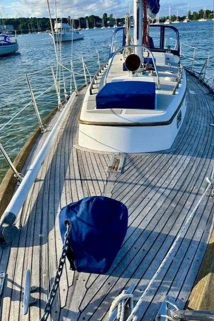 Slide: The Image of 1986 Mason 33 sailboat on water, wooden deck, blue covers, scenic marina background. - 12