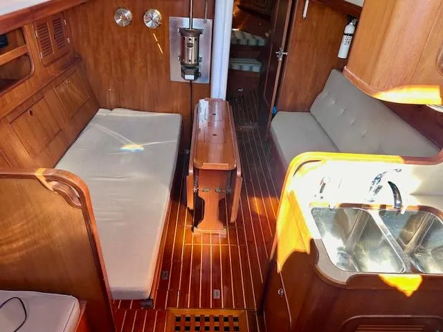 Slide: The Image of 1986 Mason 33 yacht interior with wooden finish, seating, and kitchenette. - 2