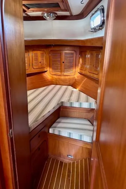Slide: The Image of 1986 Mason 33 sailboat cabin with wood paneling and striped cushions. - 20