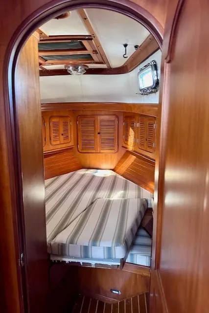 Slide: The Image of Cozy cabin interior of 1986 Mason 33 sailboat with wood paneling and striped bedding. - 21