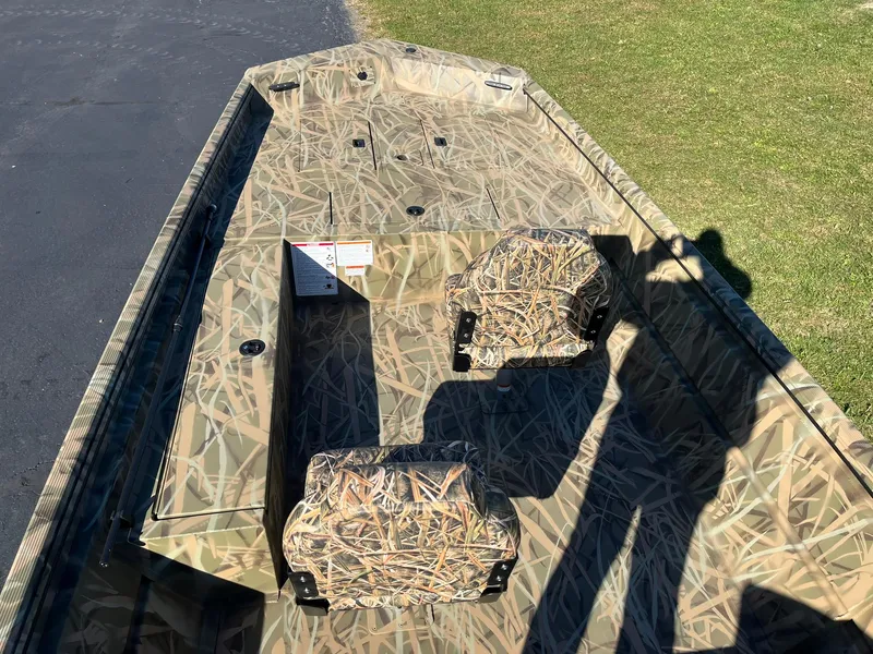 Slide: The Image of 2025 Lowe Roughneck 1760 boat with camouflage interior on grass and pavement. - 10
