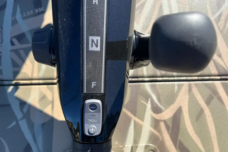 Slide: The Image of Close-up of 2025 Lowe Roughneck 1760 boat throttle control with camouflage background. - 21