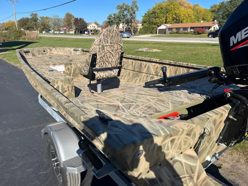 Slide: The Image of 2025 Lowe Roughneck 1760 boat with camouflage design on a trailer in a suburban area. - 8
