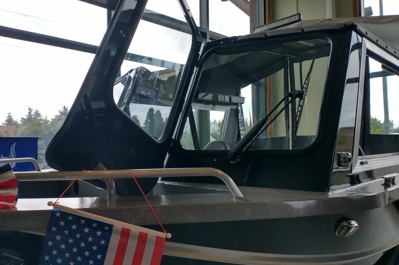 Slide: The Image of 2024 Spartan 185 Astoria boat with American flag, displayed indoors near large windows. - 7