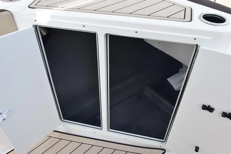 Slide: The Image of 2025 Yamaha Boats 222 FSH Sport E storage compartment with open doors. - 16