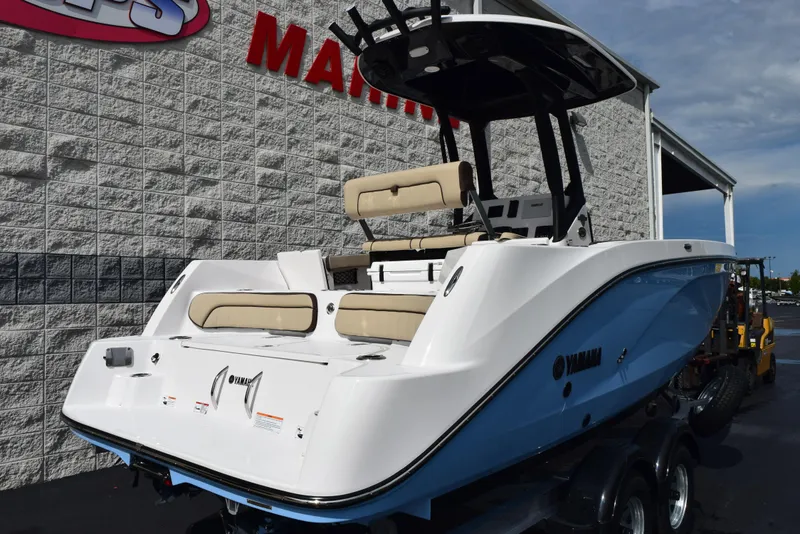 Slide: The Image of 2025 Yamaha Boats 222 FSH Sport E, white and blue, parked outside a marine dealership. - 3