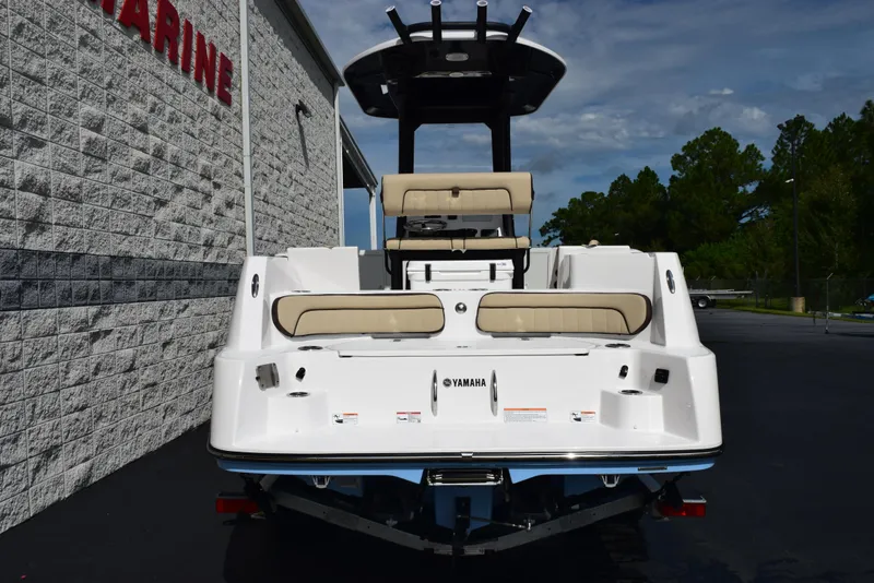Slide: The Image of 2025 Yamaha Boats 222 FSH Sport E, rear view, white exterior, beige seating, parked outdoors. - 4