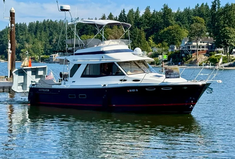 The Image of 2015 Cutwater 30CB boat docked on a scenic lake with lush greenery. - 0