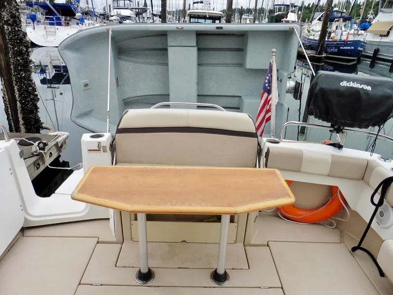 Slide: The Image of 2015 Cutwater 30CB boat interior with table, seating, and American flag in marina. - 21