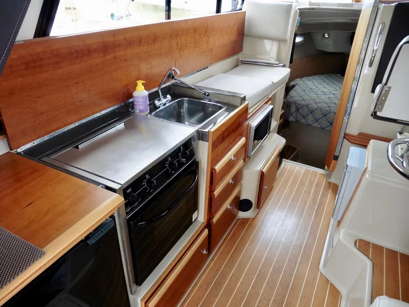 Slide: The Image of 2015 Cutwater 30CB boat interior with kitchen, sink, stove, and wood flooring. - 44