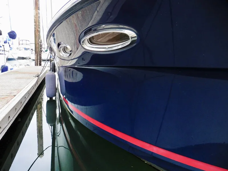 Slide: The Image of Close-up of 2015 Cutwater 30CB boat docked, featuring sleek blue hull and red stripe. - 7
