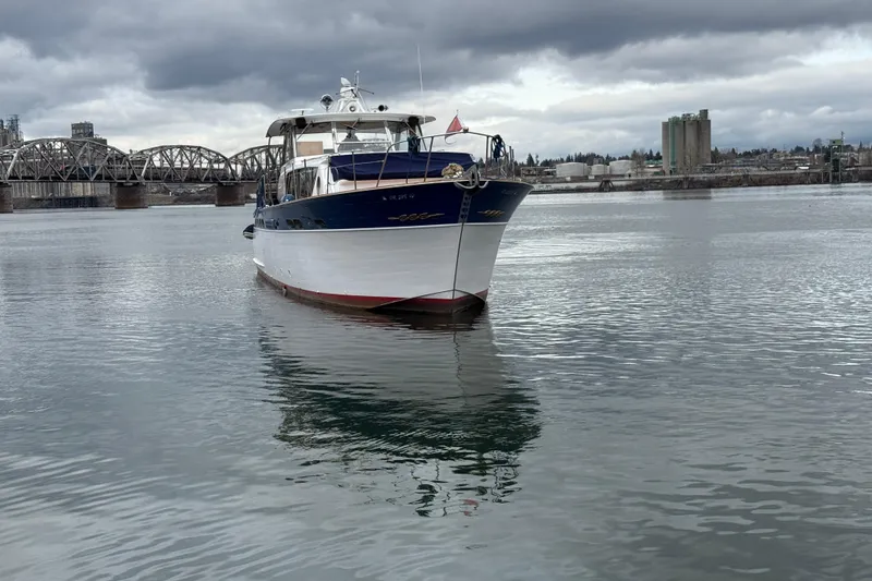 Slide: The Image of 1961 Chris-Craft 55 yacht on calm water with industrial bridge background. - 12