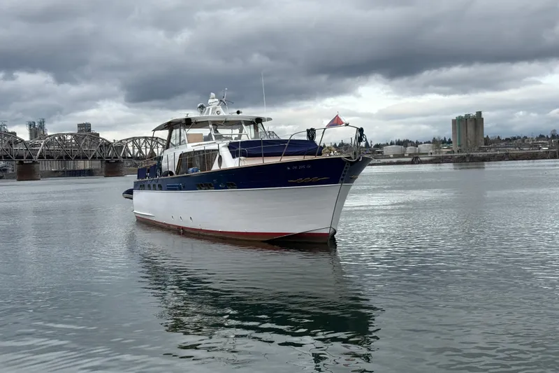 Slide: The Image of 1961 Chris-Craft 55 yacht on calm water with industrial backdrop and cloudy sky. - 13