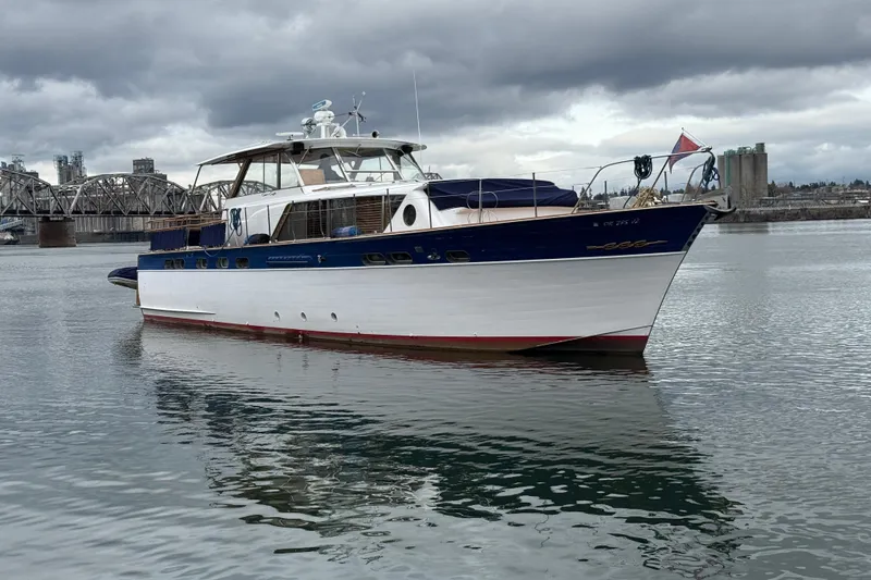Slide: The Image of 1961 Chris-Craft 55 yacht on calm water, overcast sky, near industrial bridge. - 14