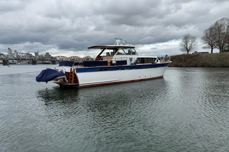Slide: The Image of 1961 Chris-Craft 55 yacht on a calm river, with a bridge and cloudy sky. - 19