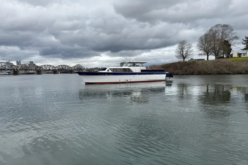 Slide: The Image of 1961 Chris-Craft 55 yacht on a calm river with a bridge and cloudy sky. - 2