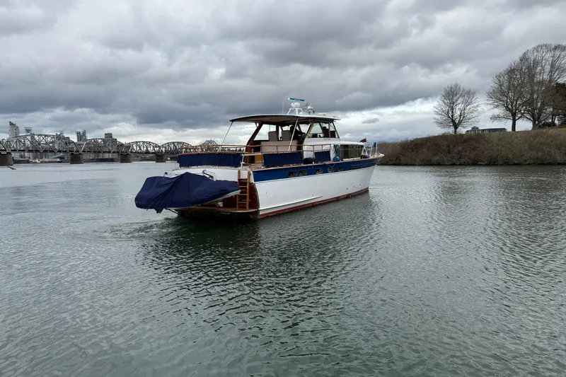 Slide: The Image of 1961 Chris-Craft 55 yacht cruising on a river with a bridge in the background. - 21