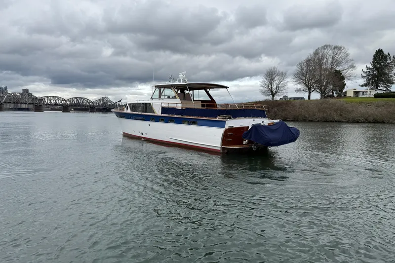 Slide: The Image of 1961 Chris-Craft 55 yacht on a cloudy day near a bridge and shoreline. - 23