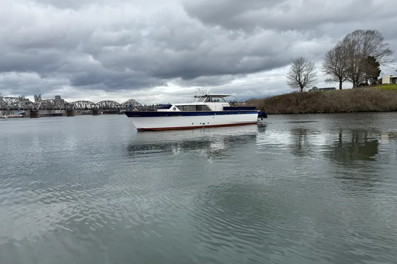 Slide: The Image of 1961 Chris-Craft 55 yacht on a calm river with a cloudy sky backdrop. - 3