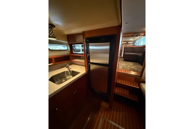Slide: The Image of 1961 Chris-Craft 55 yacht interior with kitchen sink, stainless steel fridge, and wooden flooring. - 43