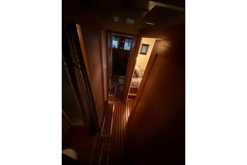 Slide: The Image of Narrow hallway inside a 1961 Chris-Craft 55 yacht, featuring wooden flooring and cozy lighting. - 46