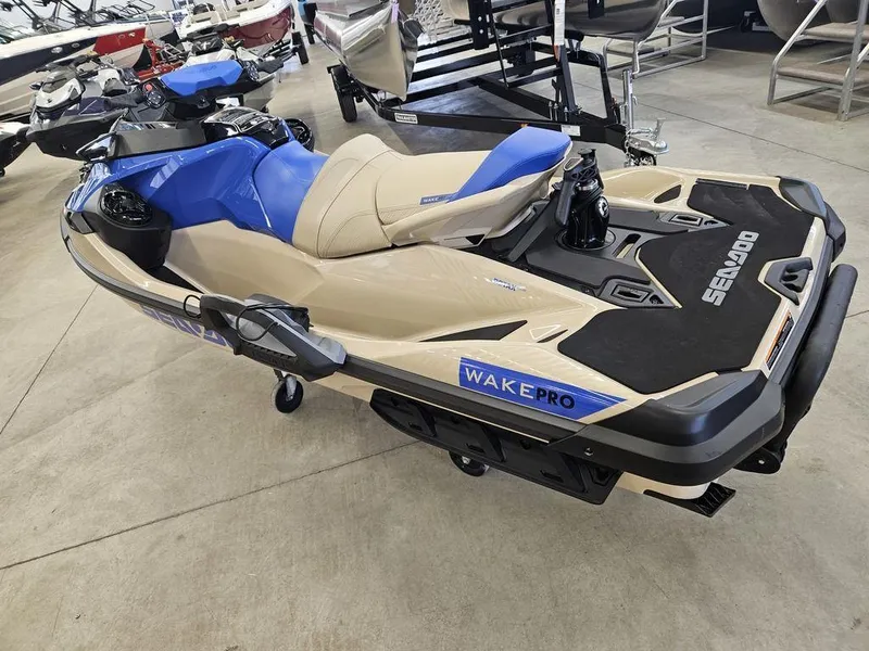 Slide: The Image of 2025 Sea-Doo WAKE™ PRO 230 jet ski in showroom, beige and blue design. - 10