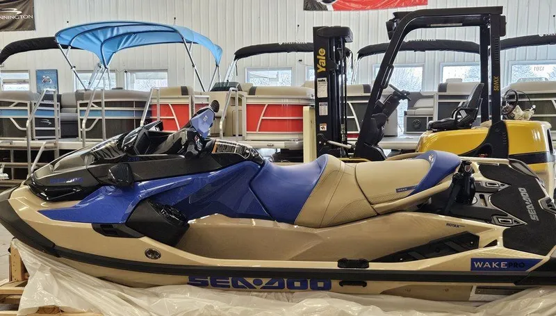 Slide: The Image of 2025 Sea-Doo WAKE™ PRO 230 jet ski in showroom, blue and beige design. - 8