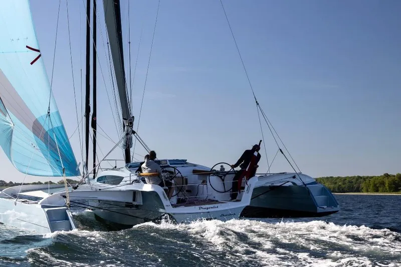 Slide: The Image of Sailing on a Dragonfly 36 trimaran, 2026 model, in open waters under clear skies. - 2