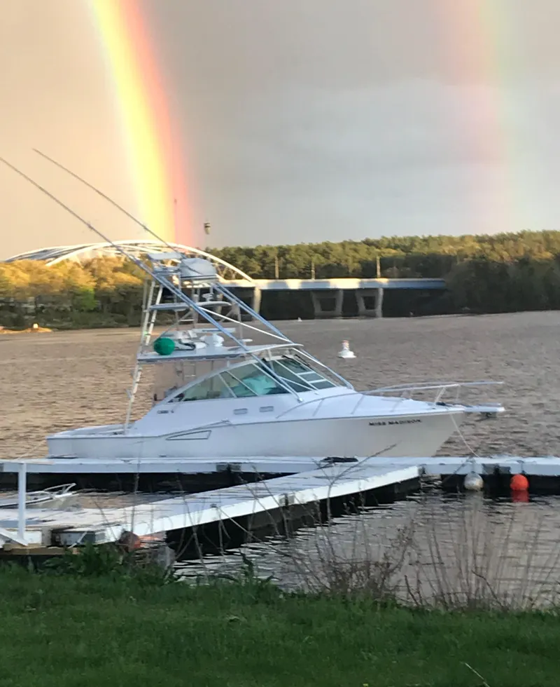 The Image of 2003 Cabo Express boat docked by a lake with a vibrant rainbow in the background. - 0