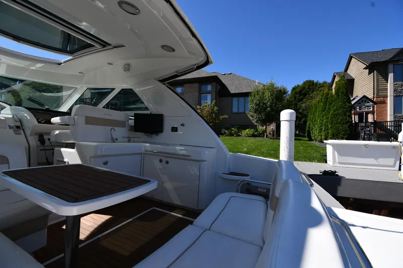 Slide: The Image of 2010 Sea Ray 450 Sundancer yacht interior with seating and table, docked near houses. - 22