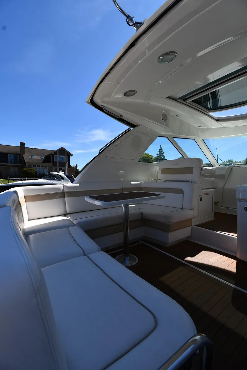 Slide: The Image of 2010 Sea Ray 450 Sundancer yacht interior with white seating and table under blue sky. - 25