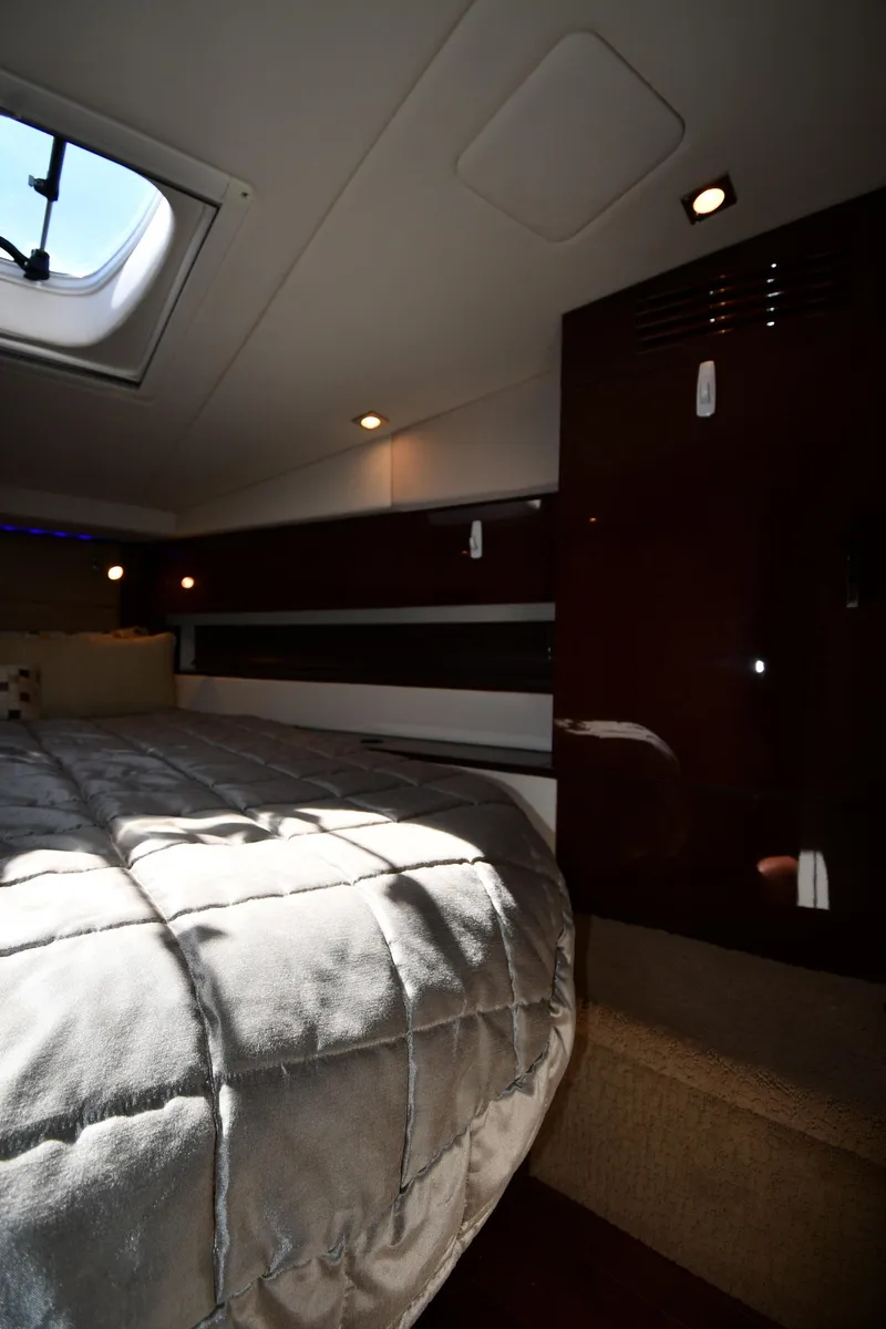 Slide: The Image of Interior cabin of 2010 Sea Ray 450 Sundancer yacht, featuring a cozy bed and elegant wood finishes. - 35
