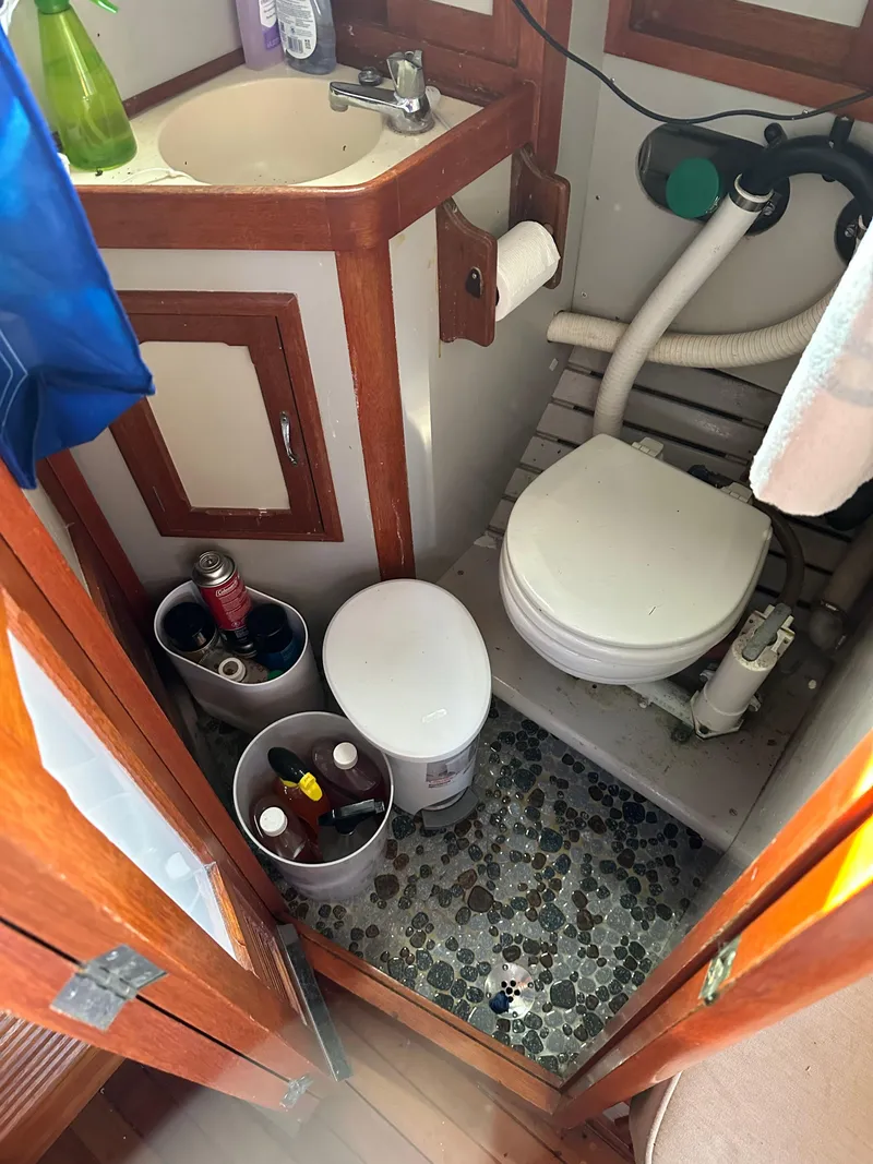 Slide: The Image of 1972 Mariner 31 Ketch bathroom with sink, toilet, and storage containers. - 11