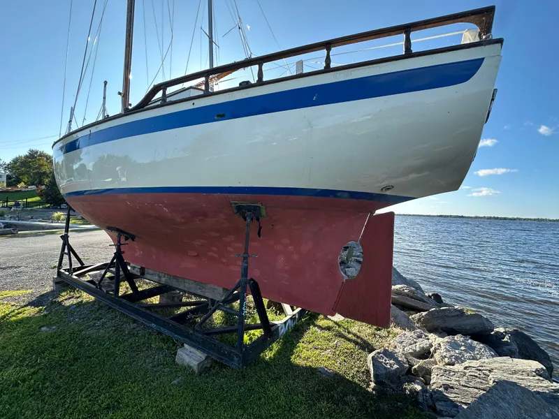 Slide: The Image of 1972 Mariner 31 Ketch sailboat on stand by the water, clear sky background. - 2