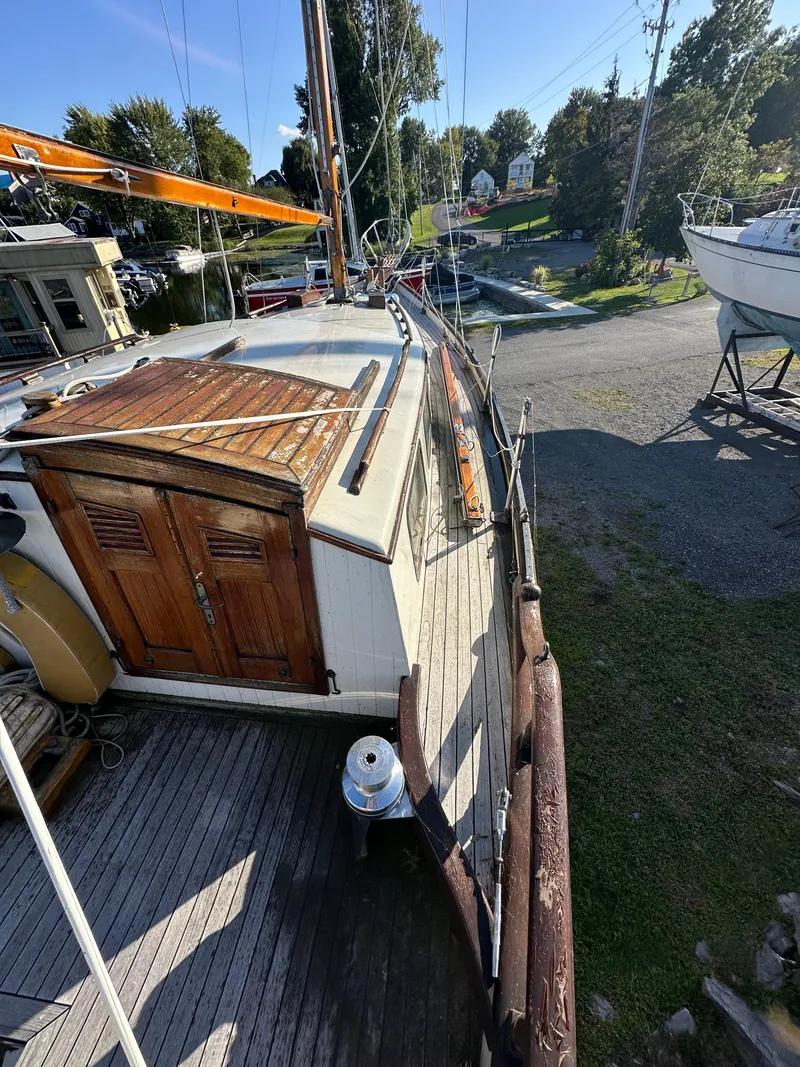 Slide: The Image of 1972 Mariner 31 Ketch sailboat on land, wooden deck and cabin, sunny day. - 9