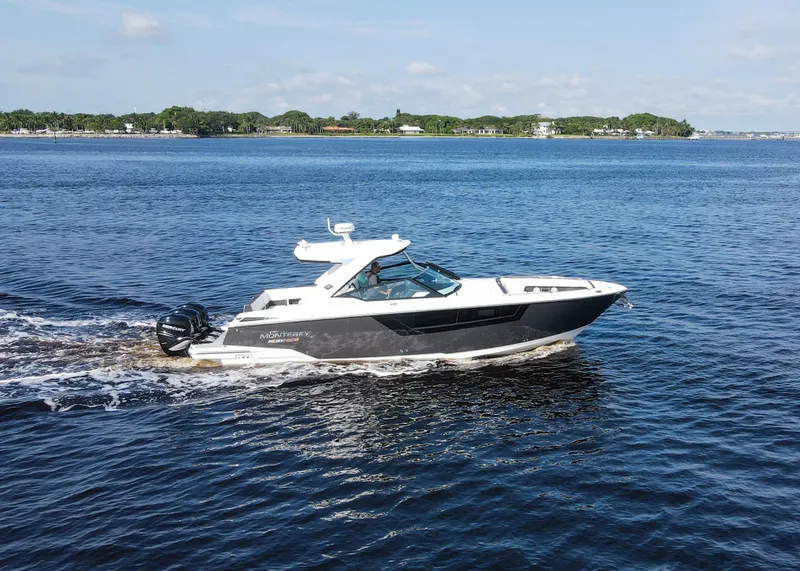 Slide: The Image of 2023 Monterey 385 Super Sport cruising on a serene lake under a clear sky. - 10