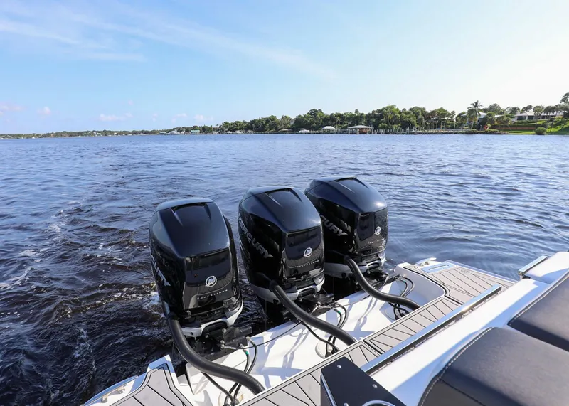 Slide: The Image of 2023 Monterey 385 Super Sport boat with triple outboard engines on a calm lake. - 16
